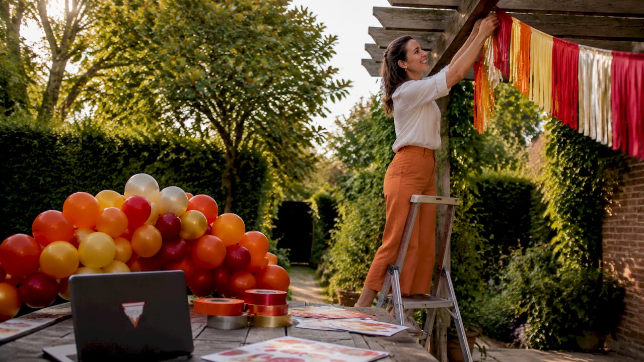 Een vrouw is bezig met het ophangen van decoraties in de woonkamer.