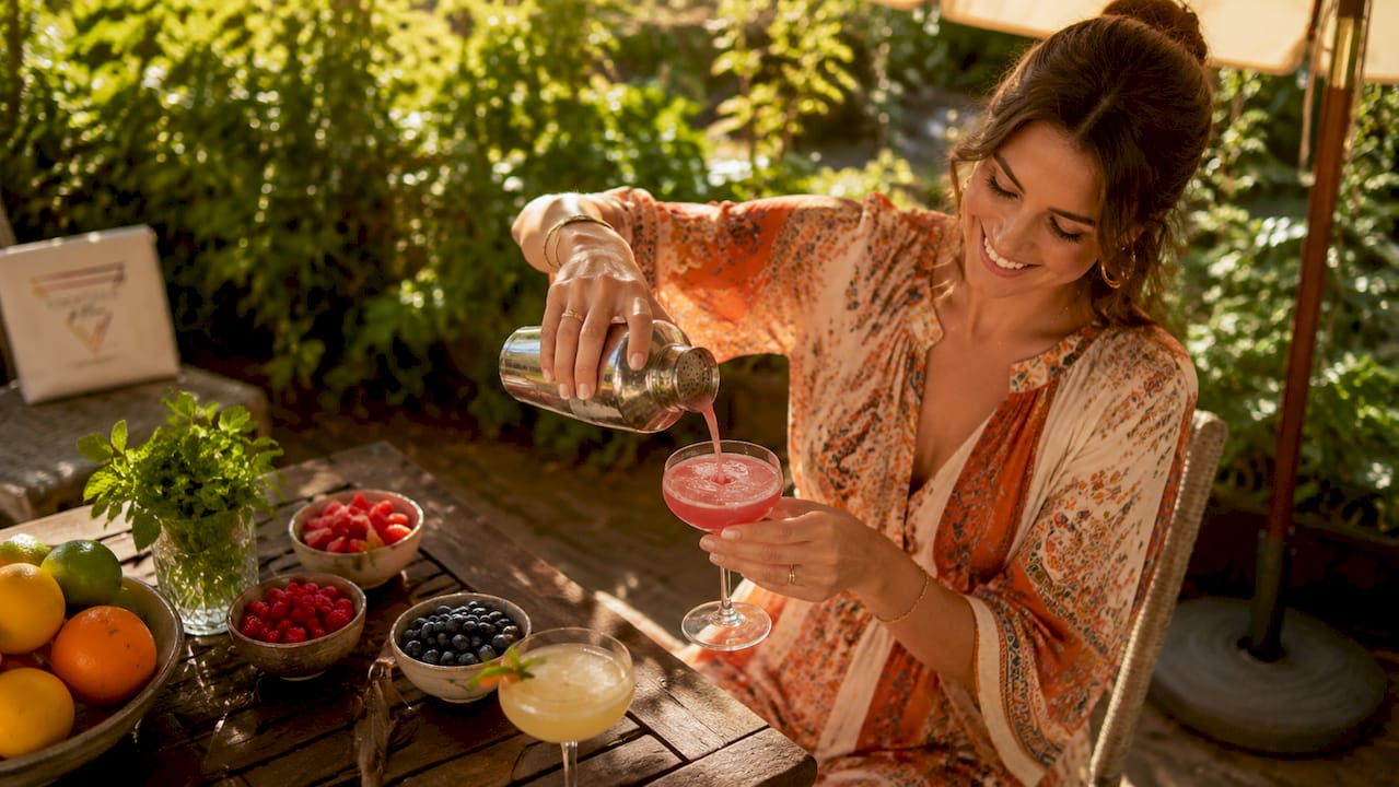 Vrouw schenkt cocktail in tijdens een gezellig huisfeest