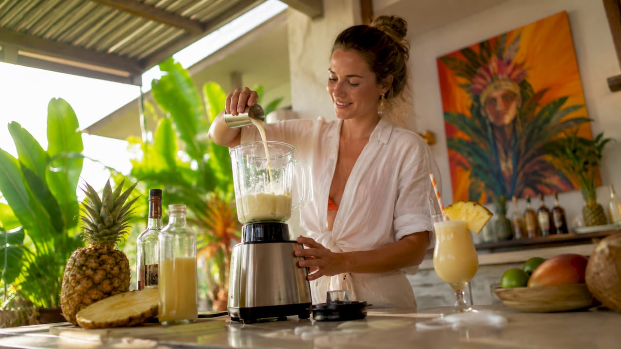 Een vrouw bereidt in haar keuken een klassieke piña colada.