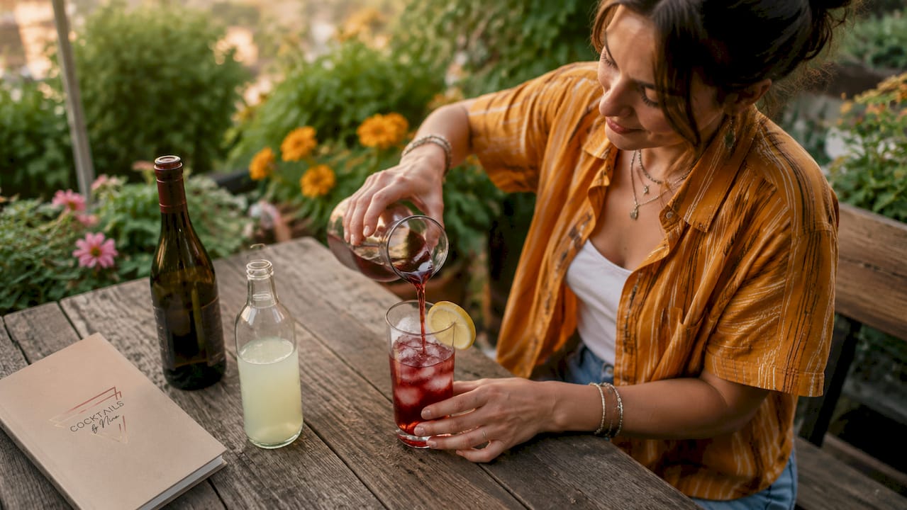 Vrouw maakt een Aperol Spritz klaar, gewoon met de hand, zonder gebruik van een shaker of mixer.