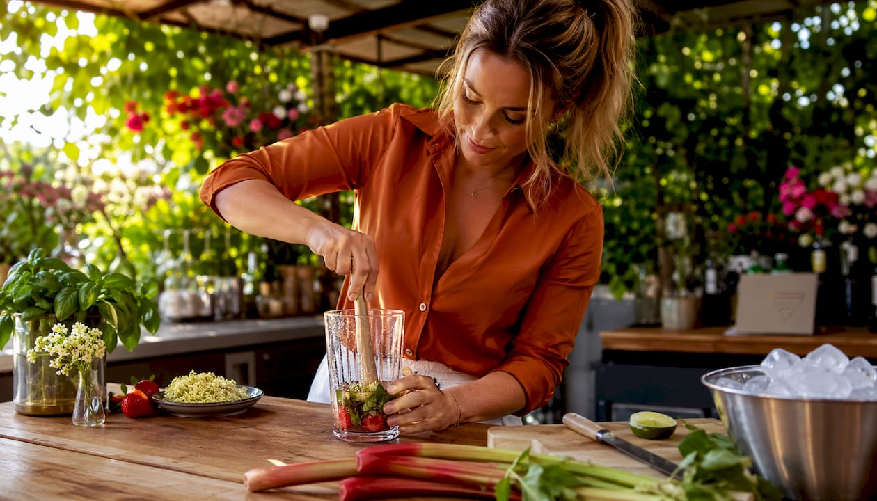 Een bartender prikt verse aardbeien fijn voor een zomerse cocktail.
