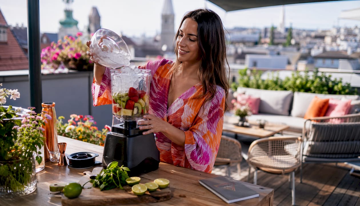 Een vrouw staat in haar eigen keuken een frisse, ijskoude cocktail te maken.
