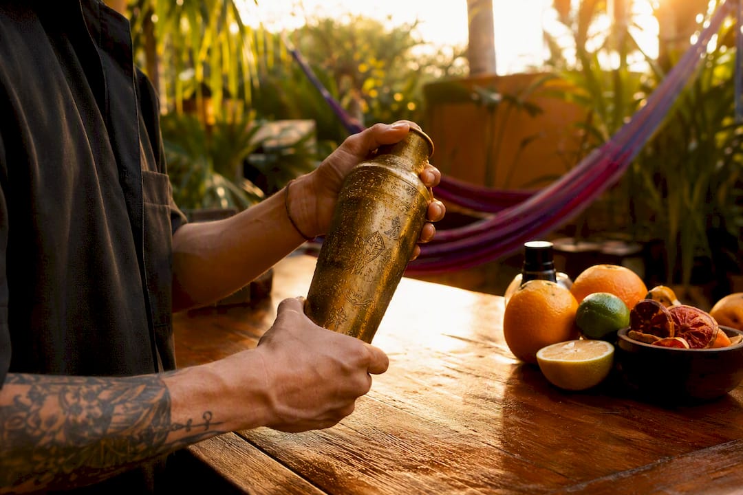 Achter de bar staat de bartender een klassieke tiki-cocktail vakkundig te shaken.
