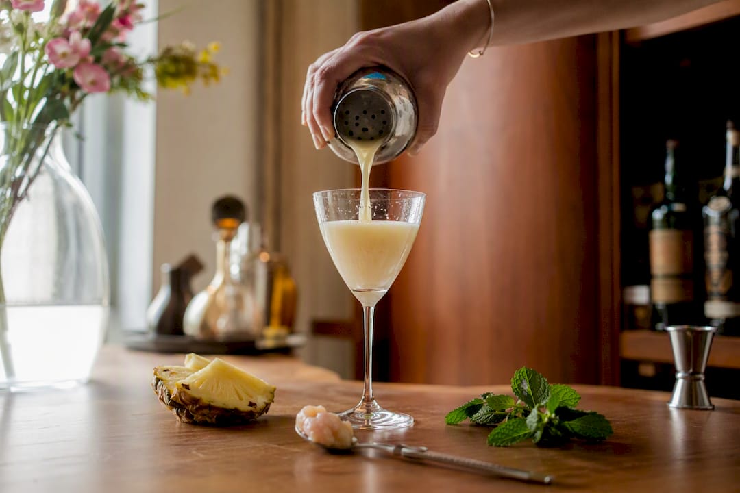 Handen schenken een zachte cocktail in een gekoeld glas