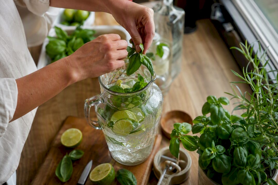 Handen die munt in een glas kneuzen voor een cocktail