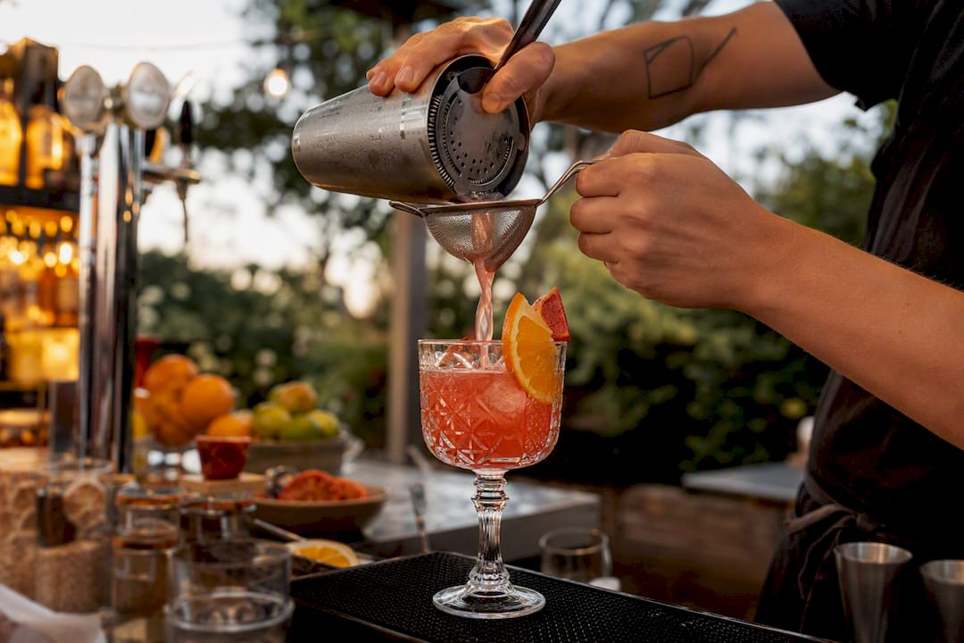 Handen die een cocktail inschenken tijdens een bedrijfsfeest