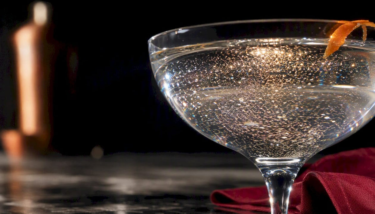 Eetbare glitters dwarrelen door een cocktailglas