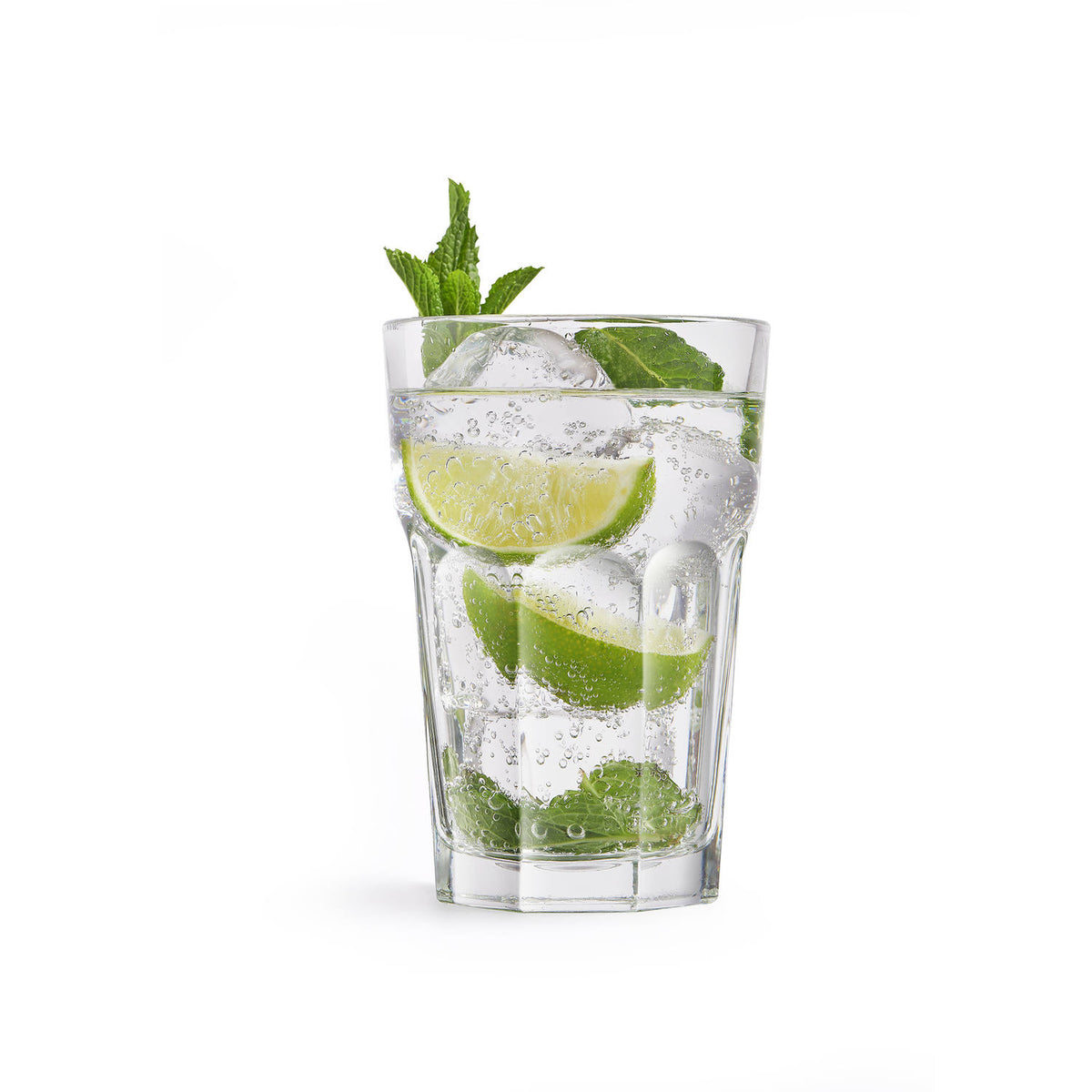 Mojito glass filled with ice, lime wedges, mint leaves, and sparkling water on a white background.-Cocktails by Nina