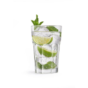 Mojito glass filled with ice, lime wedges, mint leaves, and sparkling water on a white background.-Cocktails by Nina